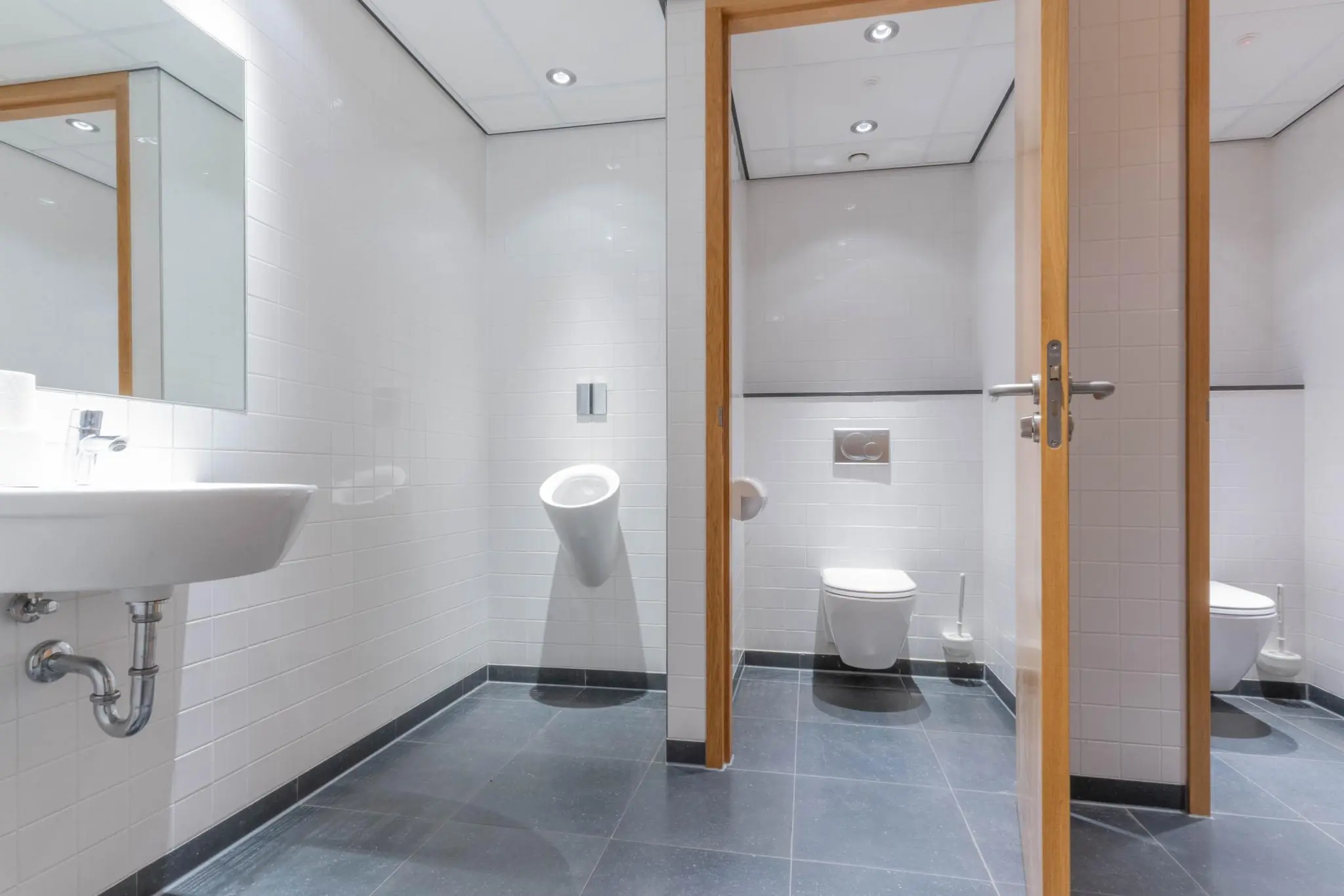 Moderne, strak afgewerkte openbare toiletruimte met urinoir, toilet en wastafel in 1e Hogeweg.